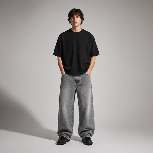 Person wearing a black t-shirt and gray jeans standing against a plain background