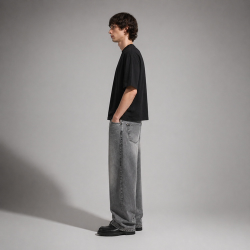 Person wearing a black t-shirt and gray jeans standing against a plain background