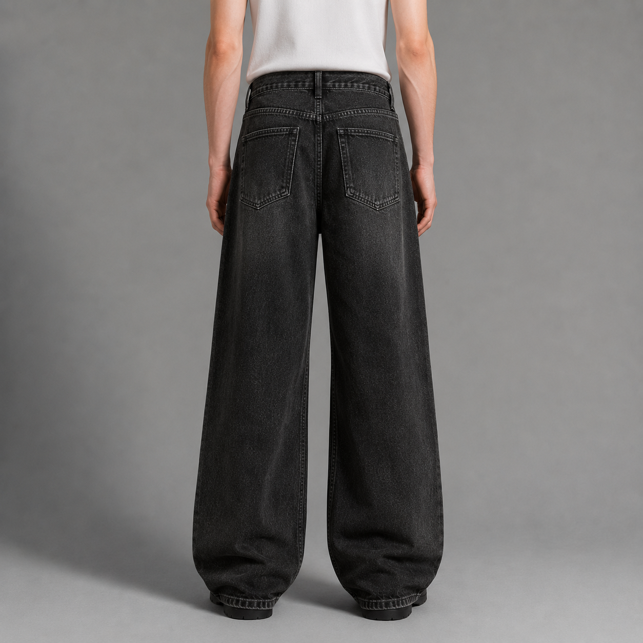 Person wearing black wide-leg jeans on a gray background
