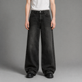 Person wearing black wide-leg jeans on a gray background