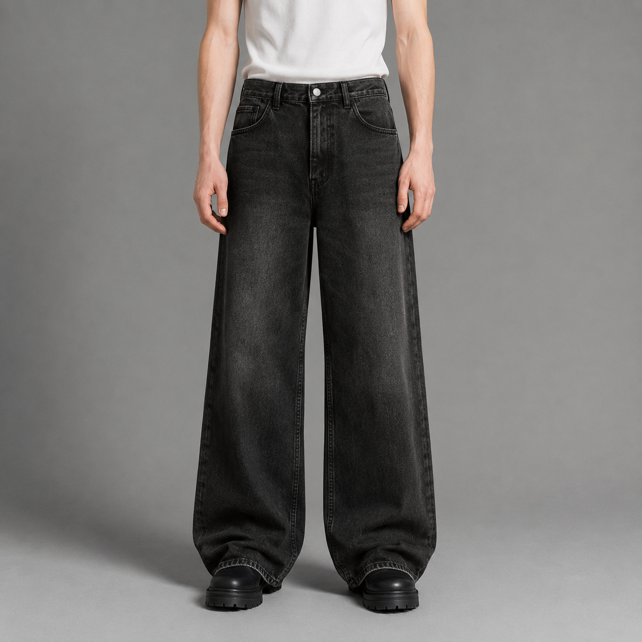 Person wearing black wide-leg jeans on a gray background