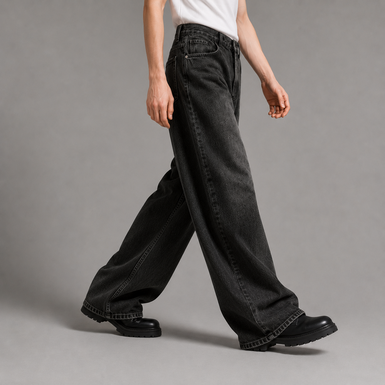Person wearing black wide-leg jeans and black shoes on a gray background