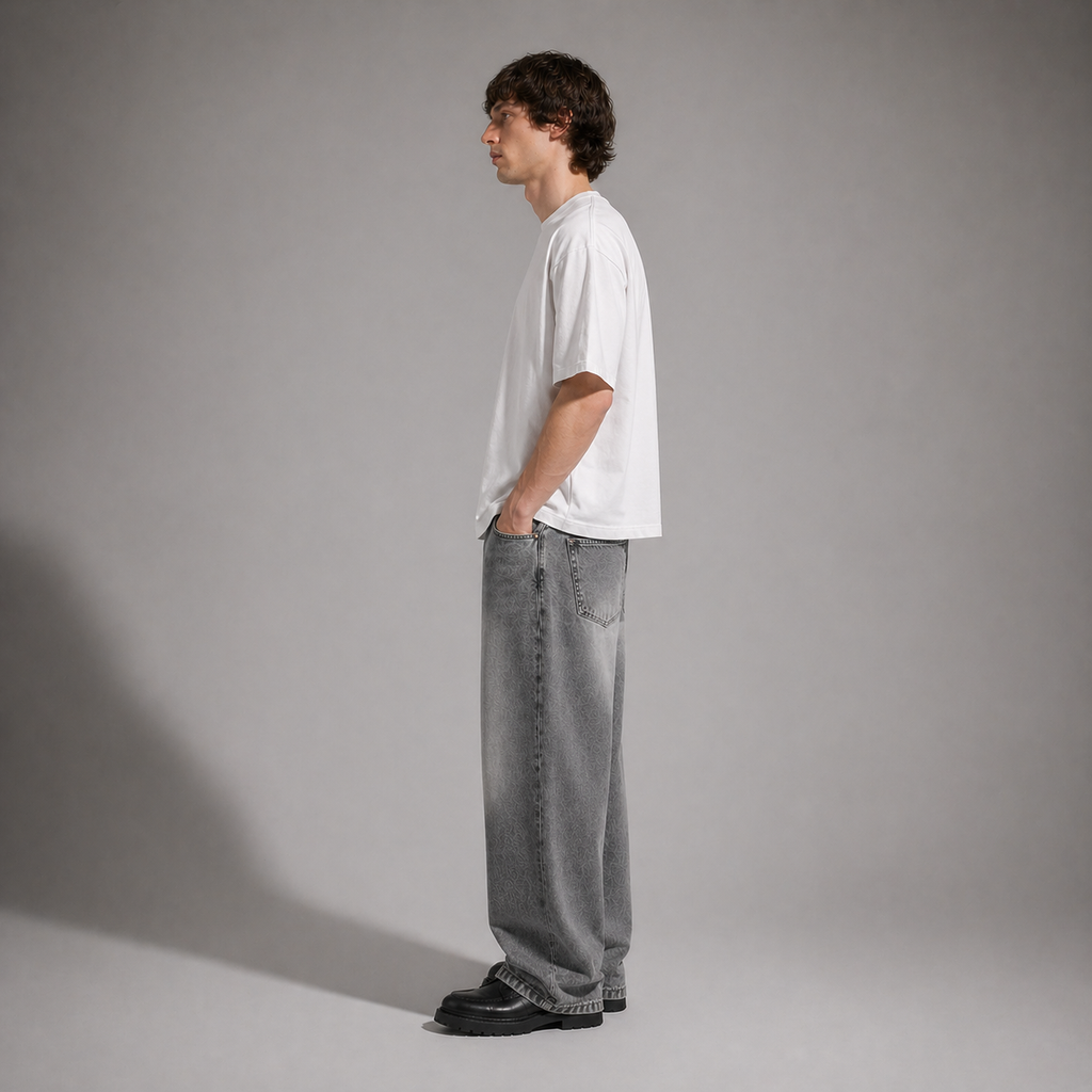 Person wearing a white t-shirt and gray jeans standing against a plain background