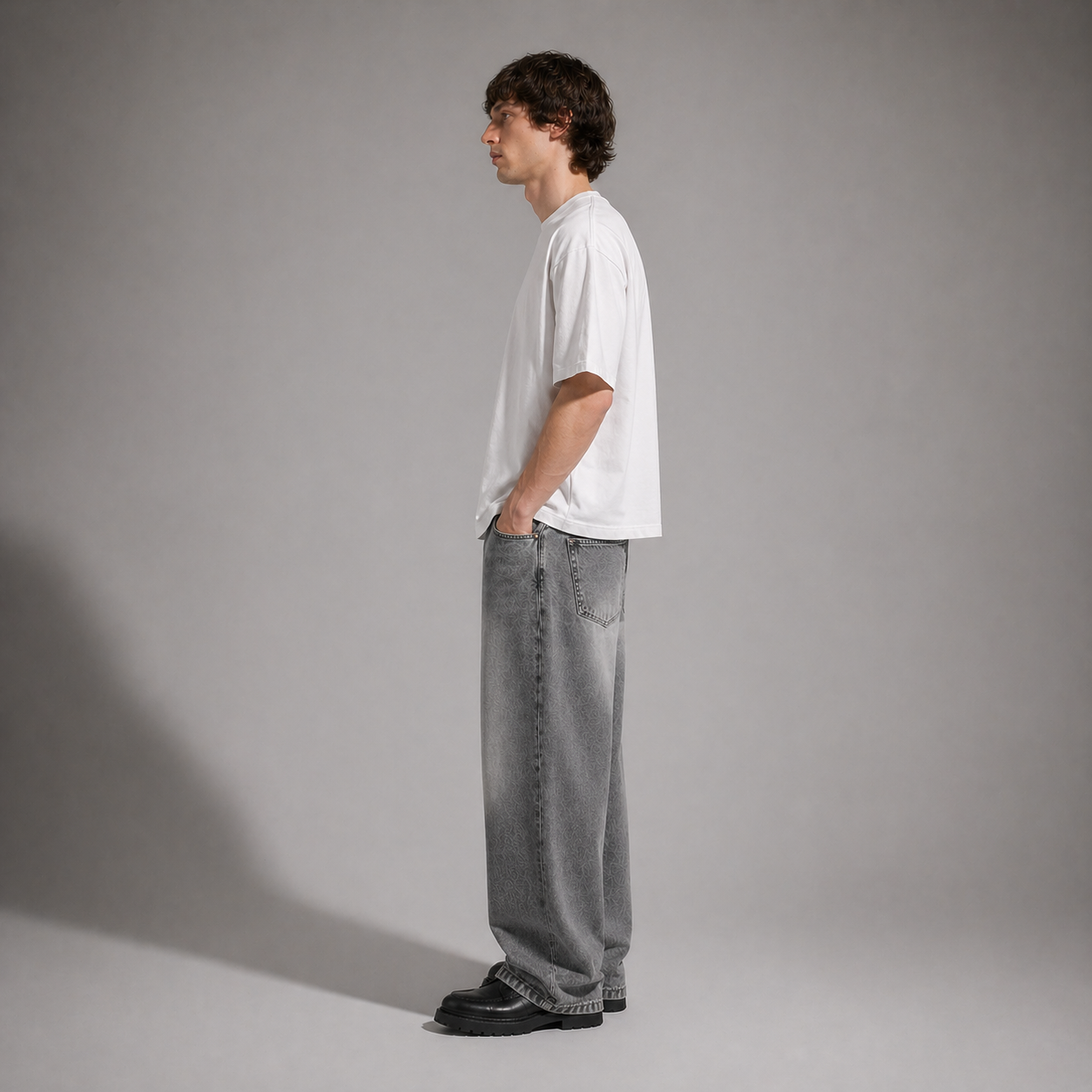 Person wearing a white t-shirt and gray jeans standing against a plain background