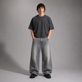 Person wearing a dark gray t-shirt and light gray jeans against a plain background