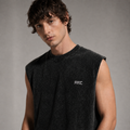 A man wearing a dark charcoal gray sleeveless crewneck t-shirt with a small white 'ARC' logo on the left chest, photographed against a neutral gray background.