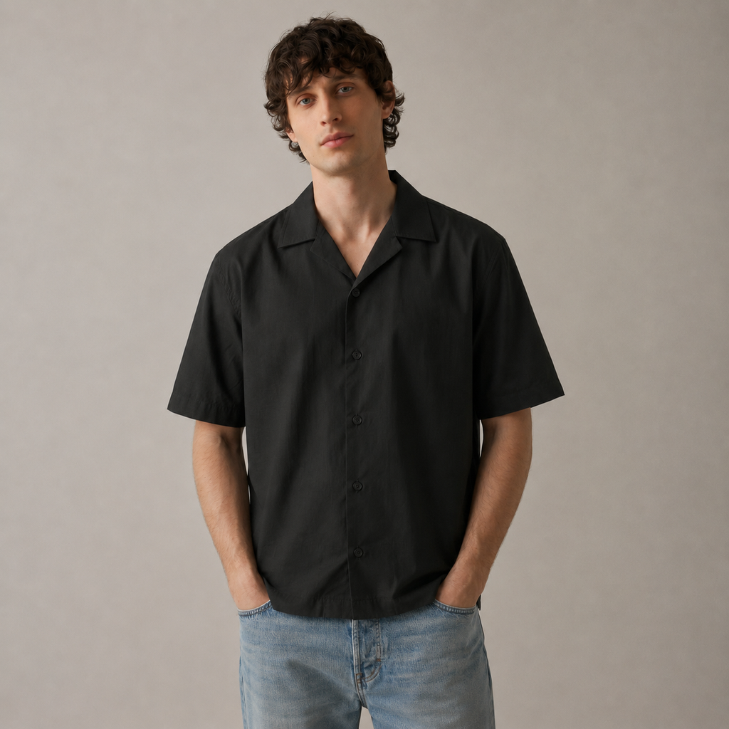 Man wearing a black short-sleeve shirt and blue jeans against a plain background
ARC Black Boxy Fit Shirt front view featuring a clean black design, relaxed boxy fit, and modern men's streetwear aesthetic.