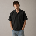 Man wearing a black short-sleeve shirt and blue jeans against a plain background
ARC Black Boxy Fit Shirt front view featuring a clean black design, relaxed boxy fit, and modern men's streetwear aesthetic.