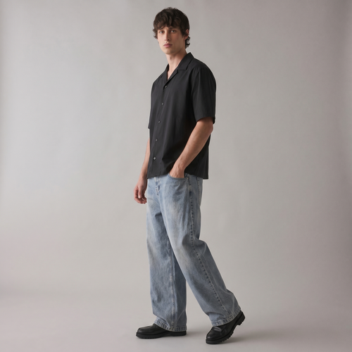 Man wearing a black shirt and light blue jeans against a plain background
Three-quarter angle of ARC Black Boxy Fit Shirt showcasing the premium black fabric, boxy fit, and contemporary streetwear style.