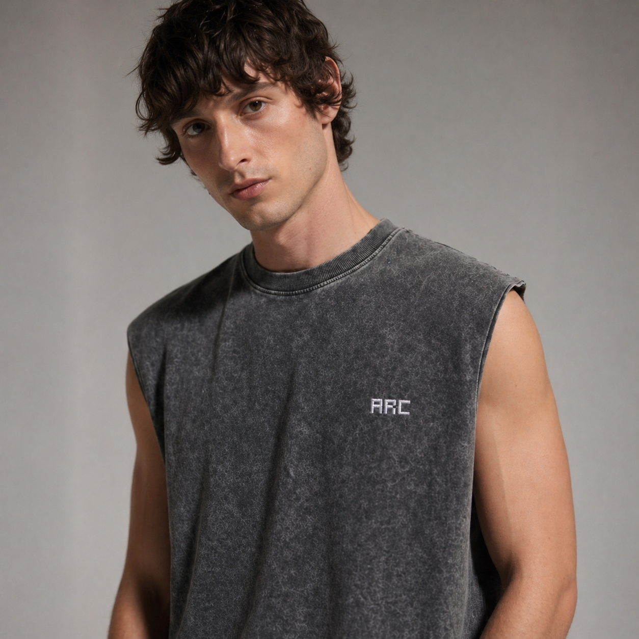 Man wearing a gray sleeveless shirt with 'ARC' logo against a neutral background
Close-up of ARC Sleeveless Acid Wash T-Shirt fabric showing the acid wash texture, stitching details, and premium cotton material.