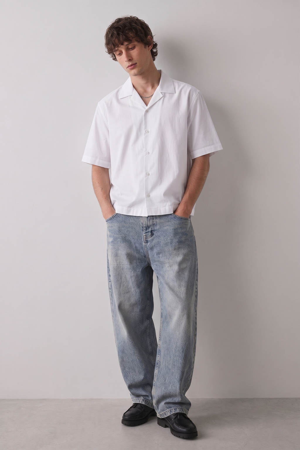 Person wearing a white shirt and light blue jeans against a plain background